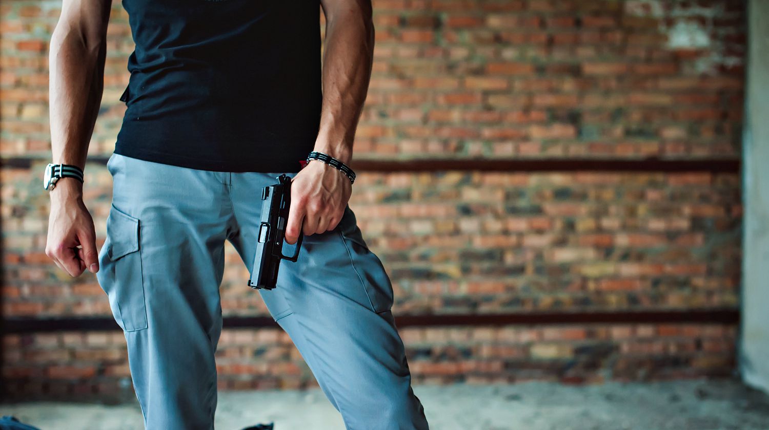 Feature | Dangerous athletic man holding a gun in his hand | Concealed Carry Tips For Gun Owners | Best Gun Concealment