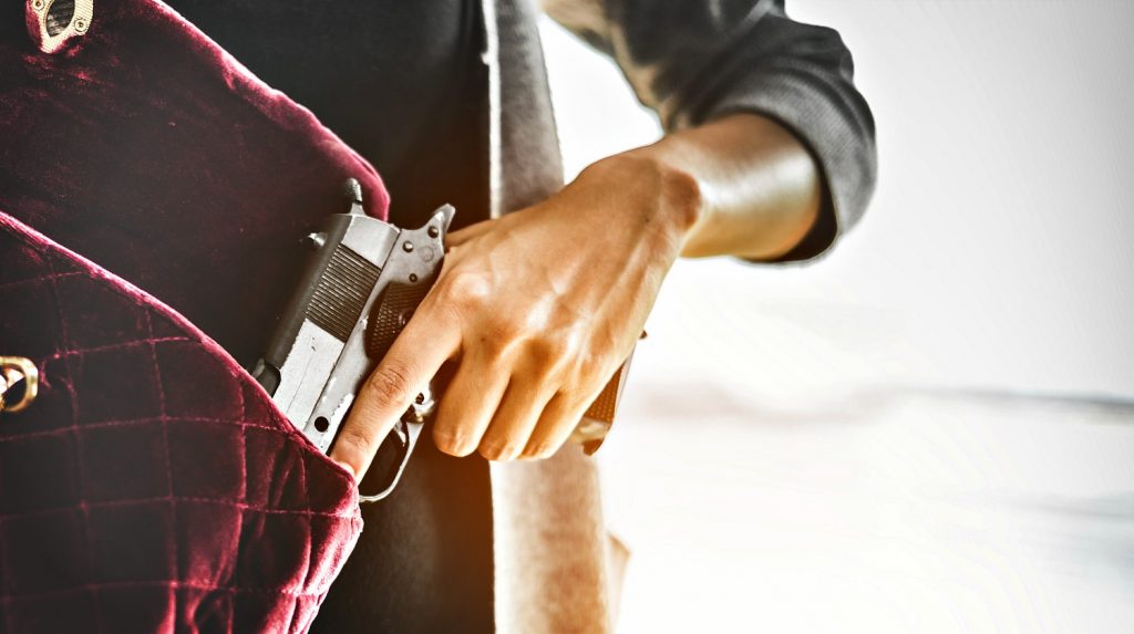 Feature | Woman holds a gun inside her bag | The Best Concealed Carry Guns For Women