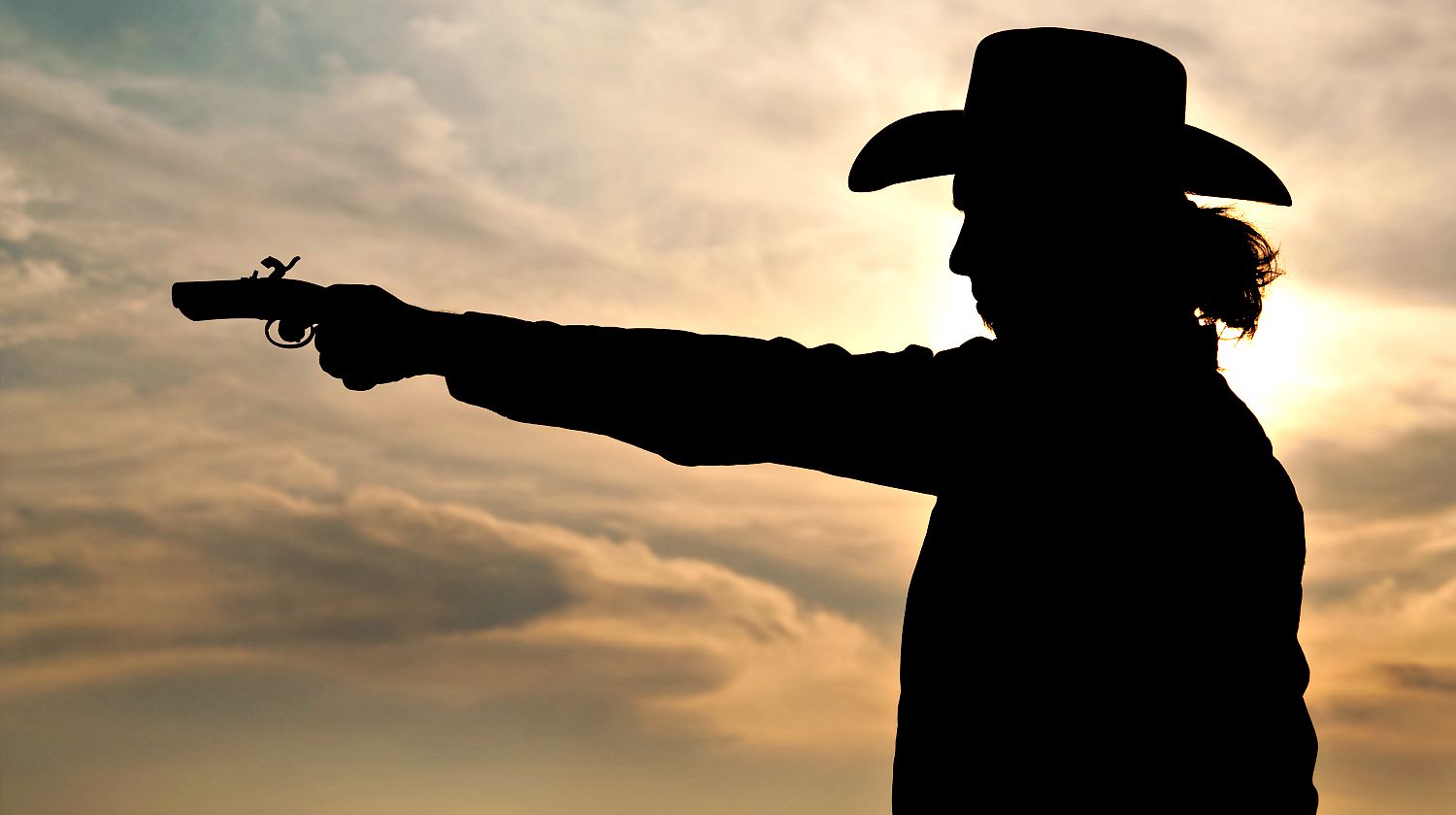 Feature| Silhouette of a young man in a cowboy hat shooting an antique hand gun | Lessons On Gunfighting From Wyatt Earp