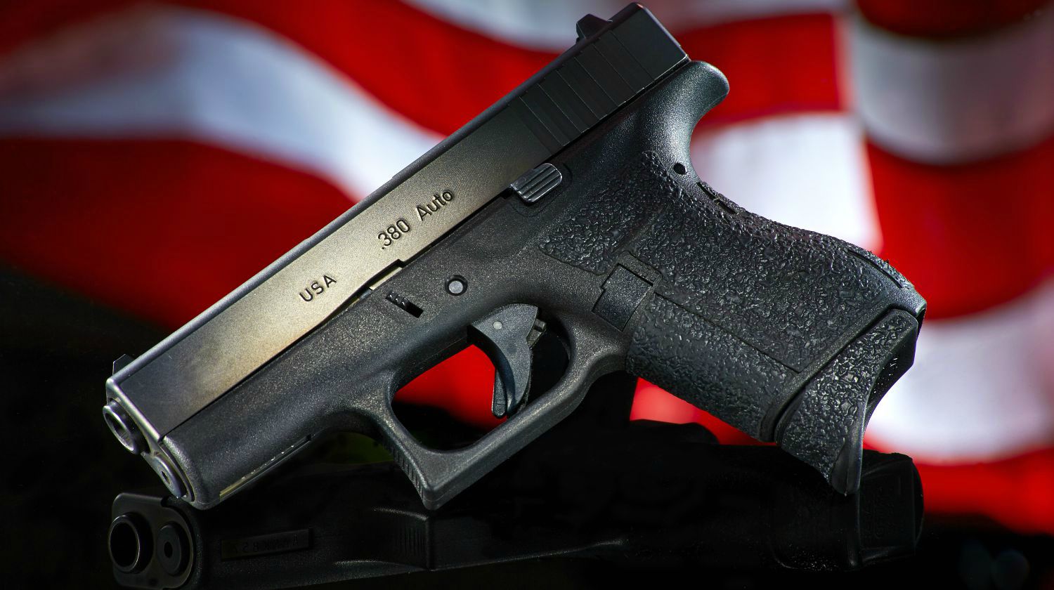 Featured | Handgun on black with flag | Concealed vs Open Carry: Pros And Cons