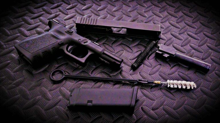 9mm pistol on black background | How To Disassemble A Glock: Step By Step Field Stripping | Featured
