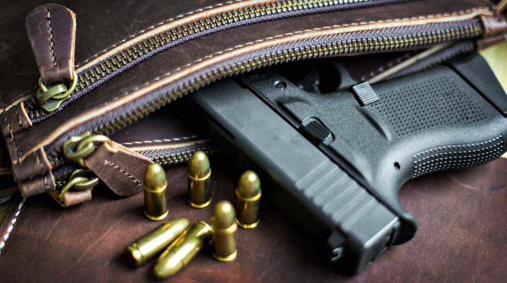 9mm Sub compact everday carry modern gun with bullet on leather background | Why I Carry A Gun, And What I Carry: An LEO's Perspective | Featured
