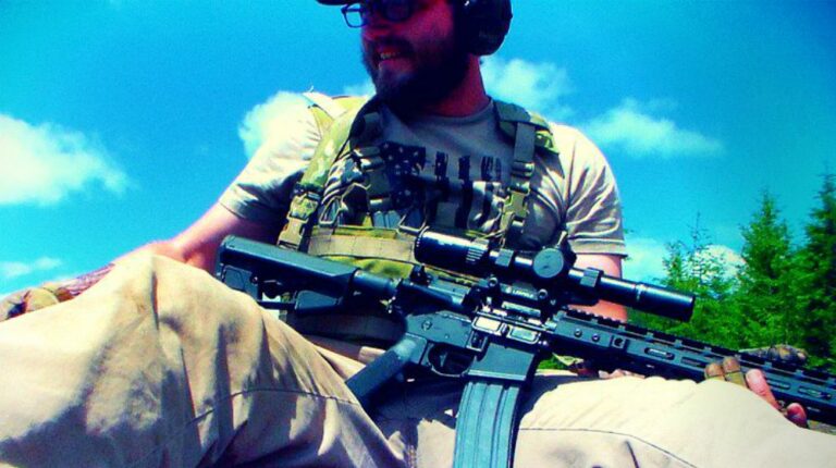 Feature | man sitting on the ground carrying a rifle | Everything You Need To Know About The AR15 Rifle Platform | ar15 history