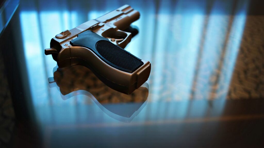 Feature | Gun on the glass table with reflection of window light | Calibers For Self-Defense | Self-Defense Firearms