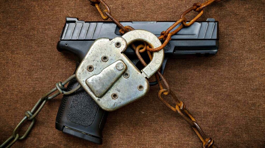 Featured | Pistol behind Lock and Chain | Gun Control | Guns The Government Will Ban First