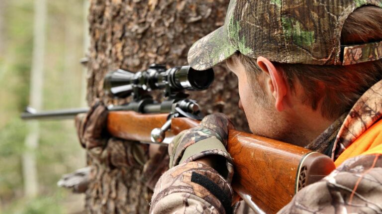 Feature | A man aiming rifle in forest | .22 Long Rifle: The Ultimate Survival Weapon?