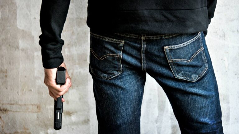 Feature | Man holding a gun side him | Beretta 21A Bobcat | Gun Carrier Handgun Review