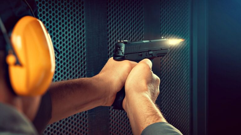 A man firing pistol at target indoor shooting range | Pistol Shooting Tips: Introduction To One-Handed Pistol Shooting | Featured