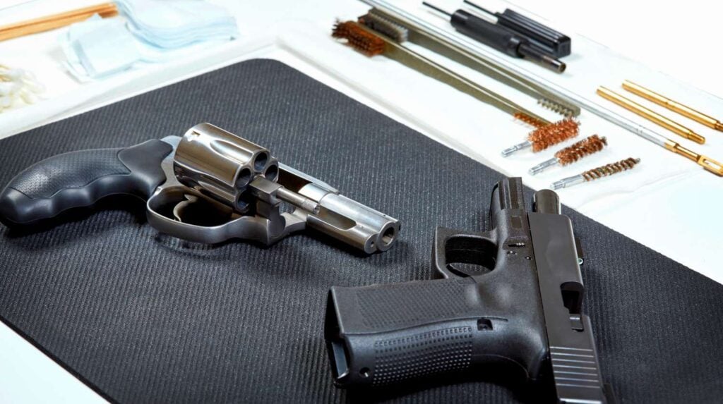 A revolver and a handgun laying on a pad in preparation for cleaning | Effective Gun Cleaning Techniques For A Happy And Clean Gun | Featured