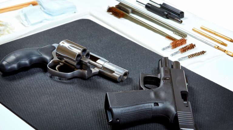 A revolver and a handgun laying on a pad in preparation for cleaning | Effective Gun Cleaning Techniques For A Happy And Clean Gun | Featured